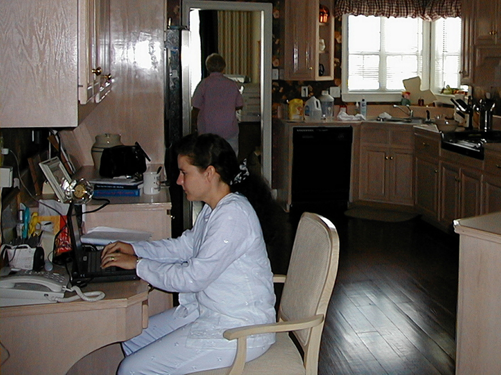 Jackie working in the kitchen while Mom walks from the kitchen into her office