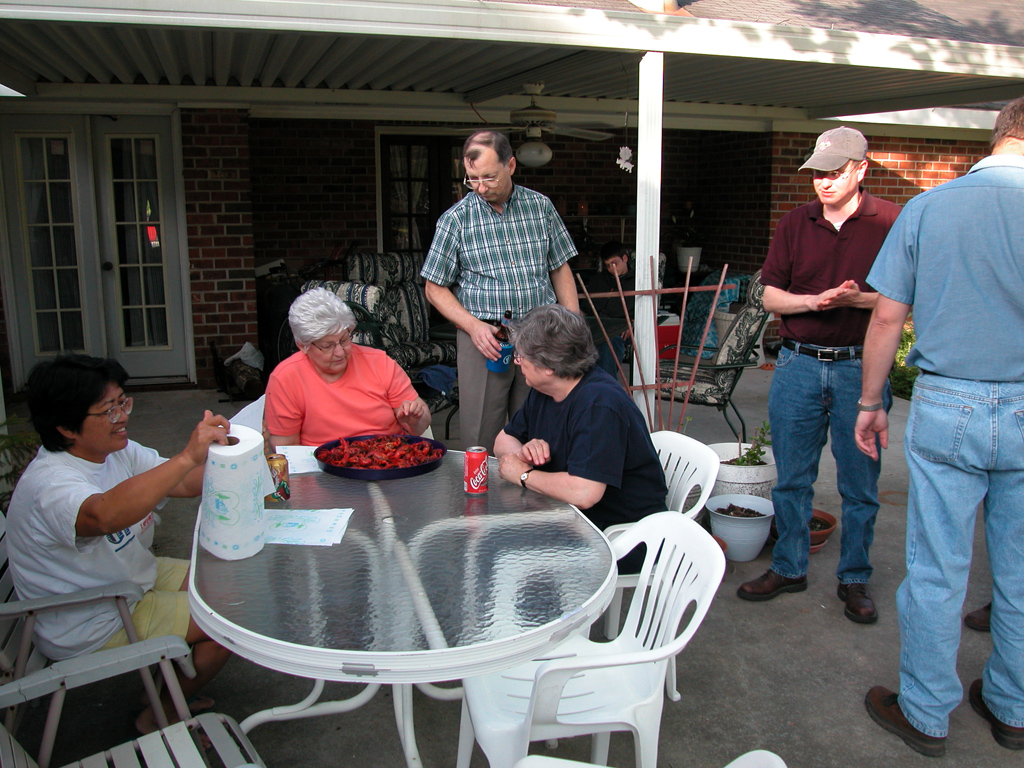 Gai, Mom, and Aunt Dory eating boiled crawfish while Felix, Marc, and Eric look on