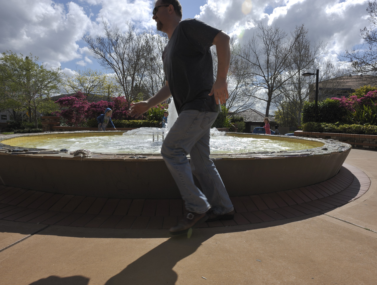 Steve chasing the kids around a water fountain
