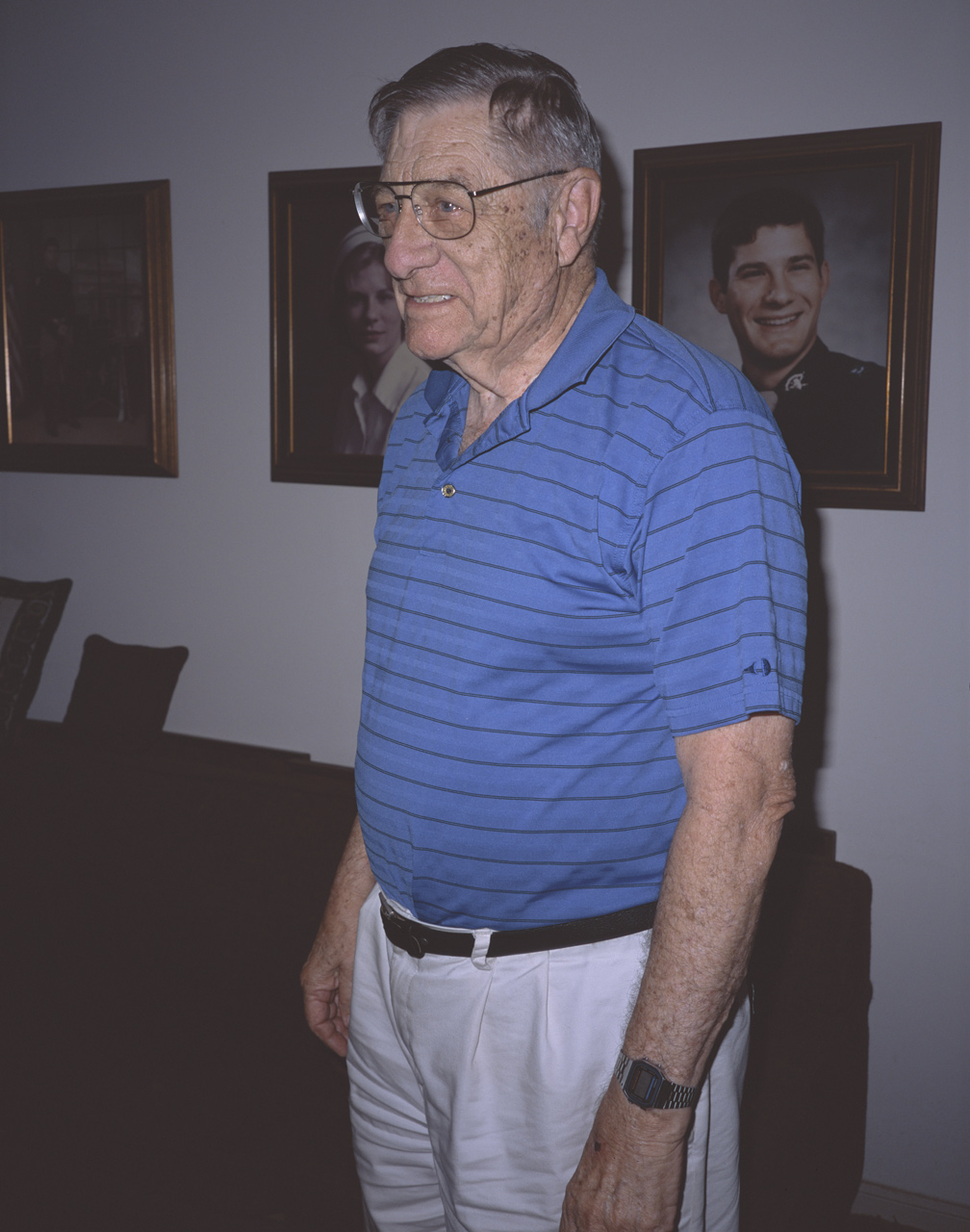 Uncle Jimmy standing in front of portraits of Jimbo, Susie, and Bill
