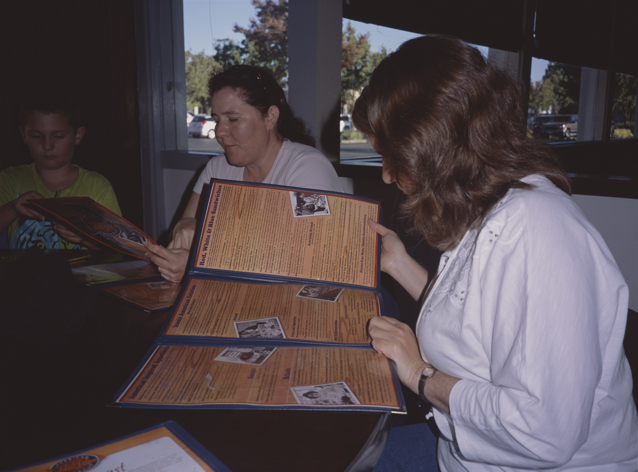 John, Jackie, and Carol examining the dinner menu at EDDIE PAPAS AMERICAN HANGOUT®