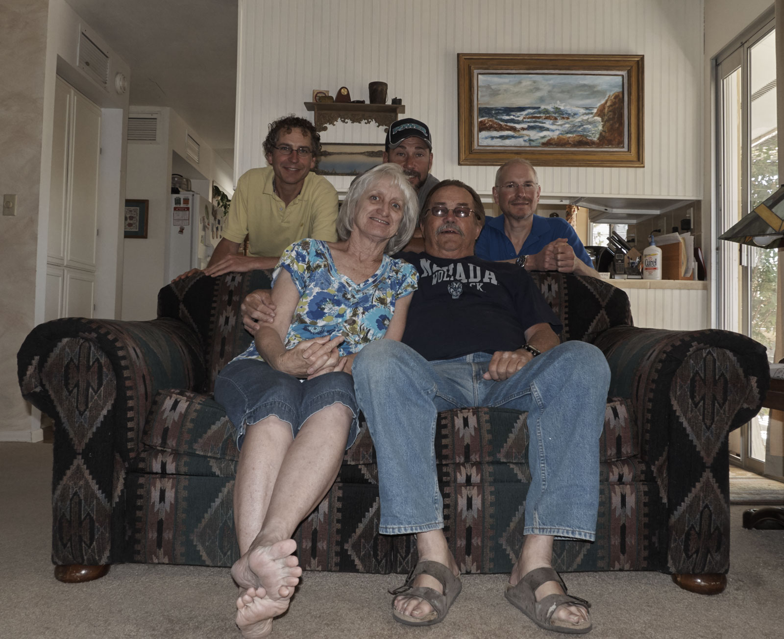 Uncle Bill and Lynne sitting on their couch, with Marc, Tom, and me behind them