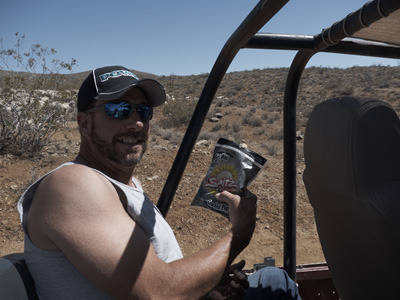 Tom munching on nutritionally challenged food in the back seat of Uncle Bill's 'land crusher', with frozen sheep in the background, in El Paso Mountains Wilderness