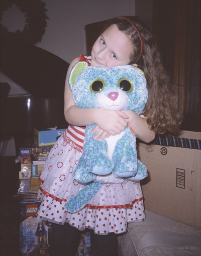 Sophia hugging 1 of her stuffed doll gifts in the piano room on Christmas morning