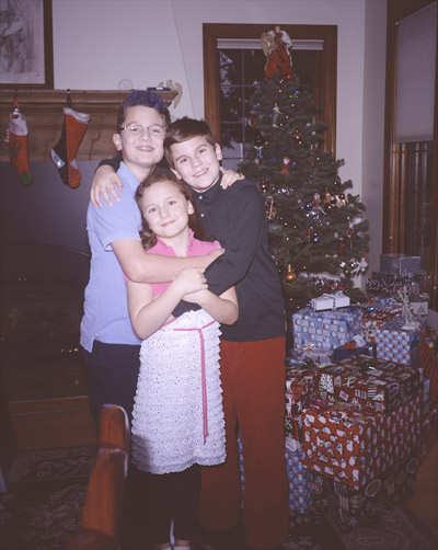 John, Sophia, and James standing before the Christmas tree and presents in the piano room on Christmas Eve