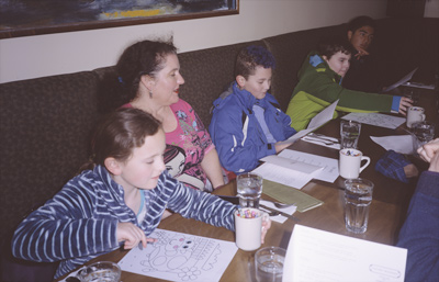 Sophia coloring, Jackie looking at John who is looking at the lunch menu, James reaching for his drink, and Mikhil looking at the menu, at PAPA HADYN