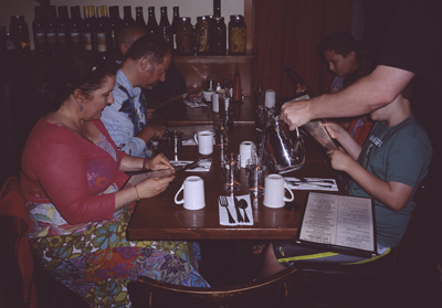 Jackie and Steve, Marc, John, Sophia, and James perusing the menu, while our server pours some water, at the SCREEN DOOR