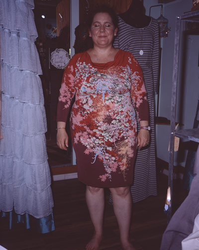 Jackie with her eyes closed, trying on a red dress inside FROCK clothing shop
